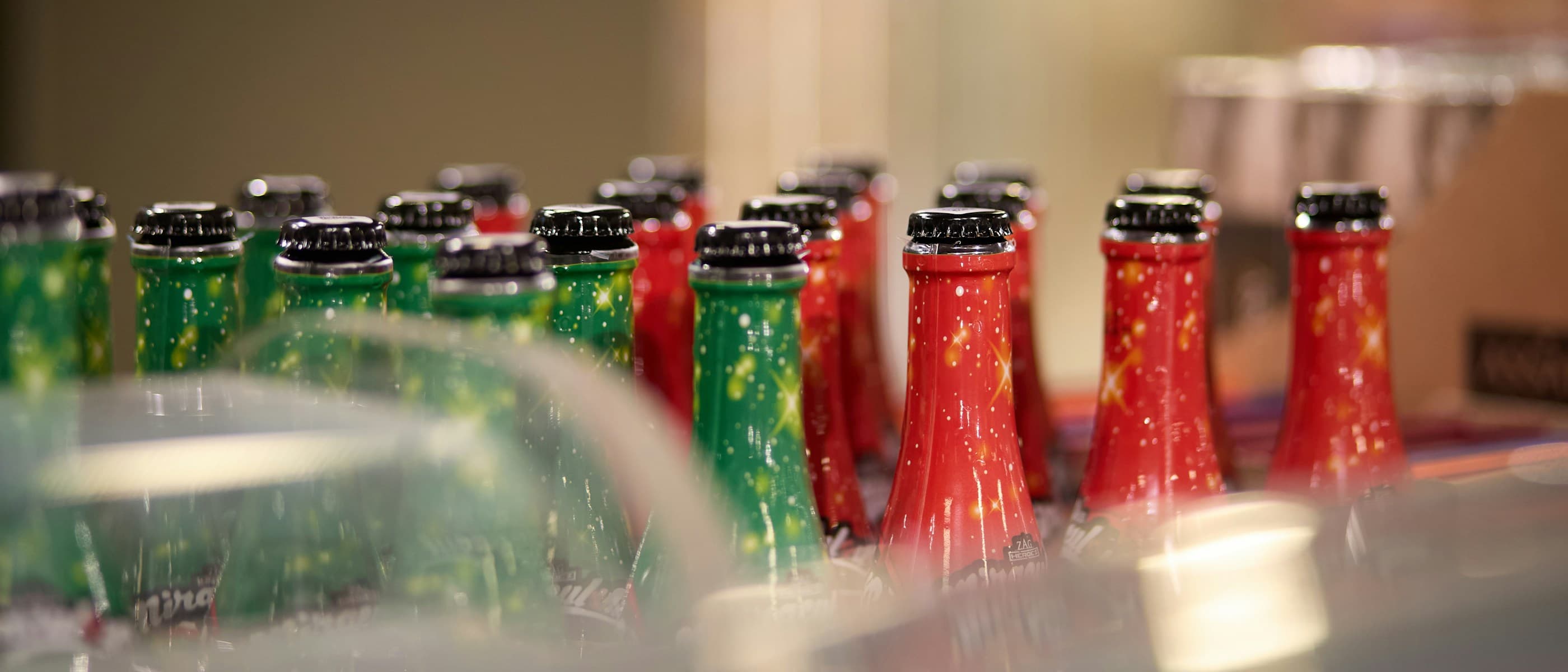 Rows of red and green beverage bottles with metal caps